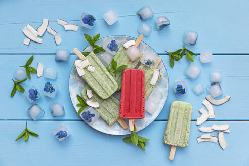 Red strawberry popsicle on plate with green mint and coconut ones - GWF07945