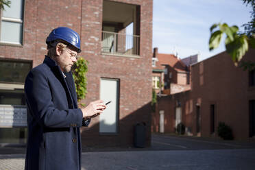 Architect using smart phone in front of buildings - KNSF10005