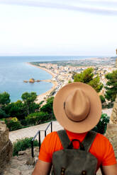 High-angle view of tourist man from behind with hat in Barcelona looking at the expansive beach coastline from a high vantage point. - ADSF49897