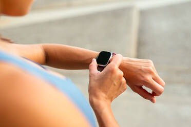 A close-up image of a Latin American woman checking her smartwatch during a workout session. - ADSF49913