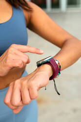 Active woman checks her smartwatch during a workout session, monitoring her activity and health metrics. - ADSF49915