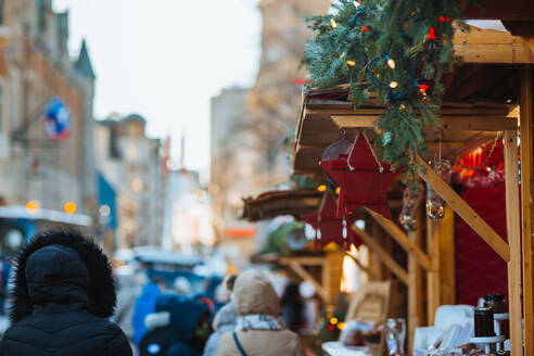 Visitors explore a festive holiday market adorned with Christmas lights and seasonal decorations, evoking the spirit of the holidays in Quebec, Canada - ADSF49939