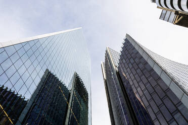 A low-angle view of modern glass skyscrapers reaching towards a clear blue sky in London’s dynamic cityscape. - ADSF49968