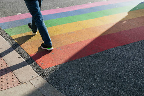 A person walking over a vibrant rainbow crossing on a sunny day in London, reflecting diversity and inclusivity. - ADSF49970