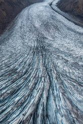 From above shot of a glacier flowing through a valley with striking blue ice patterns - ADSF49984