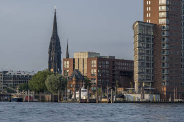 Germany, Hamburg, Riverside buildings with tower of St. Nicholas Church in background - KEBF02781