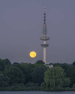Germany, Hamburg, Full moon rising over communications tower at dusk - KEBF02790