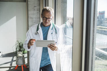 Oberarzt mit Tablet-PC am Fenster - UUF30618