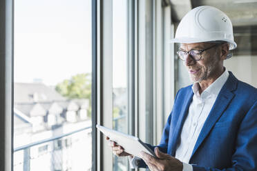 Lächelnder Ingenieur mit Tablet-PC am Fenster - UUF30649