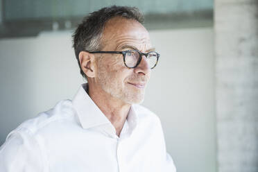 Thoughtful businessman wearing eyeglasses in office - UUF30662