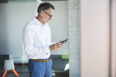 Businessman using smart phone in office - UUF30664