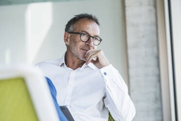 Contemplative businessman sitting in front of wall - UUF30674