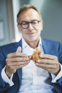 Geschäftsmann hält Holzspielzeugblöcke im Büro - UUF30684