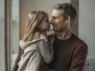 Smiling father rubbing noses with daughter at home - MFF09522