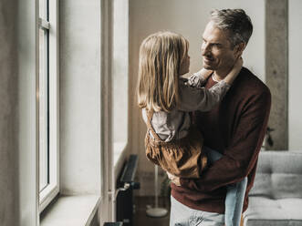 Mann steht am Fenster mit Tochter zu Hause - MFF09524