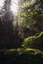 Junge Frau beim Wandern im Wald an einem sonnigen Tag - RSGF00981