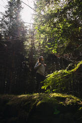 Young woman hiking in forest on sunny day - RSGF00981