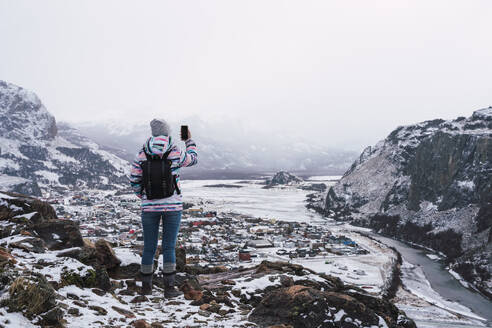 Frau fotografiert schneebedeckte Berge mit dem Smartphone - RSGF00988