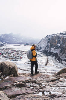 Mann trägt Rucksack und steht auf einer Klippe im Winter - RSGF00990