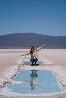 Frau hockt in der Nähe des Salzsees vor einem Berg - RSGF01000