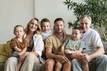 Smiling grandfather, parents and children in living room at home - SVKF01708