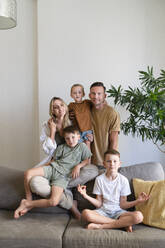 Parents sitting with sons on sofa in living room at home - SVKF01722