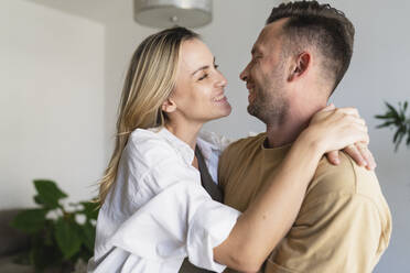 Glücklicher Mann und glückliche Frau umarmen sich zu Hause - SVKF01744