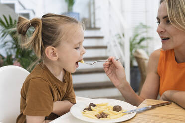 Mutter füttert einen Jungen am Esstisch mit Nudeln - SVKF01776