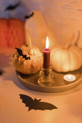 Kürbisse mit Kerzen und künstlicher Fledermaus auf dem Tisch - ONAF00703