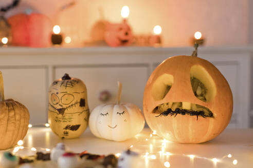 Pumpkin decorations near string light on table at home - ONAF00707