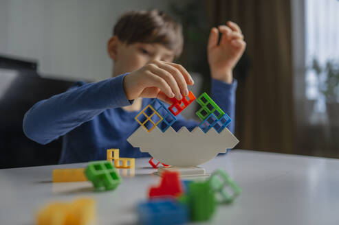 Elementary boy balancing toy blocks at home - ANAF02487