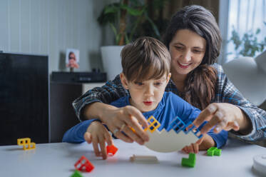 Mother and son playing with toy blocks at home - ANAF02493