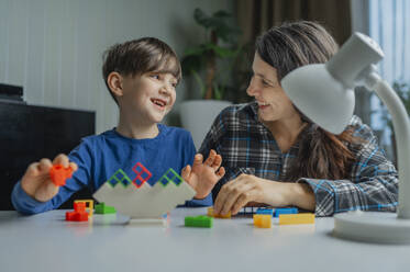 Glückliche Mutter und Sohn spielen zu Hause mit Bauklötzen - ANAF02494