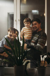 Happy family standing near window at home - ANAF02496