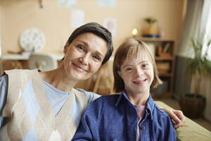 Lächelnde Mutter und ihre Tochter mit Down-Syndrom zu Hause - KPEF00405