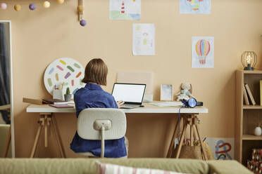 Teenage girl using laptop while studying from home - KPEF00406