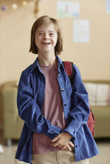 Lächelndes Teenager-Mädchen mit Down-Syndrom, das zu Hause steht - KPEF00431