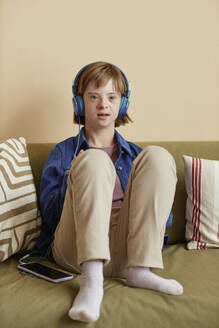 Mädchen mit Down-Syndrom hört zu Hause Musik über Kopfhörer - KPEF00432