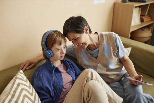 Mutter schaltet Musik auf dem Smartphone ein, wenn das Mädchen zu Hause Kopfhörer trägt - KPEF00435