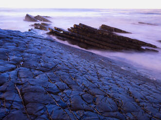 Portugal, Alentejo, Zambujeira do Mar, Long exposure of rocky beach at dusk - DSGF02450