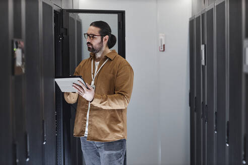 Ingenieur mit Tablet-PC bei der Arbeit im Serverraum - KPEF00475