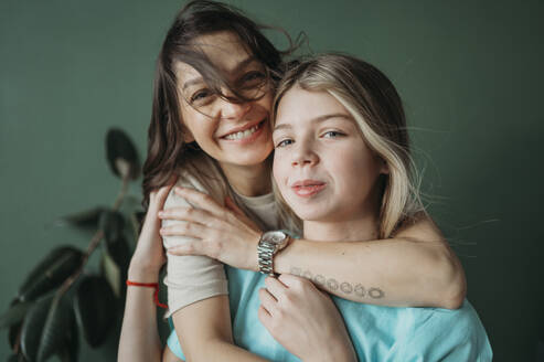 Happy mother hugging daughter at home - ANAF02522