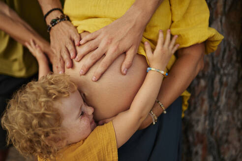 Familie berührt den Bauch der werdenden Mutter im Park - ANNF00734
