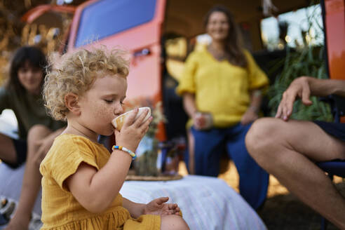 Mädchen trinkt Tee mit Familie im Park im Urlaub - ANNF00772