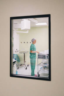 Krankenschwester im Operationssaal durch Glasfenster gesehen - MMPF01018