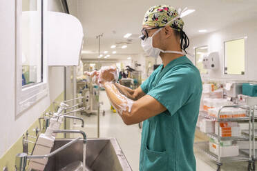 Surgeon wearing mask washing hands in hospital - MMPF01023