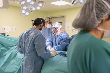 Surgeons and nurses performing surgery on patient in operating room - MMPF01026