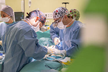 Surgeons and nurses performing surgery on patient in hospital - MMPF01031