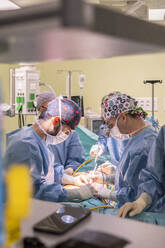 Team of surgeons performing surgery on patient in emergency room - MMPF01033