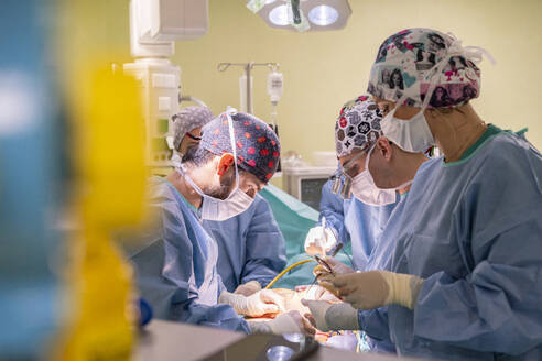 Ein Team von Chirurgen mit Masken bei der Operation eines Patienten in der Notaufnahme - MMPF01034